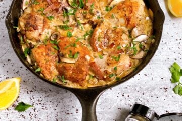Skillet full of Black Garlic Chicken in a mustard cream base with mushrooms and parsley.