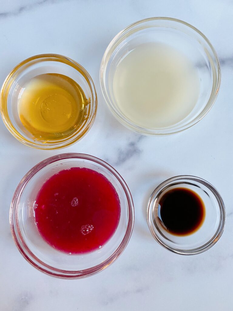 Overhead view of Sparkling Blood Orange cooler ingredients: freshly squeezed blood orange juice, honey, vanilla and sparkling water