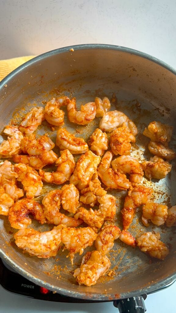 A close up view of chopped, seasoned and cooked shrimp in a skillet
