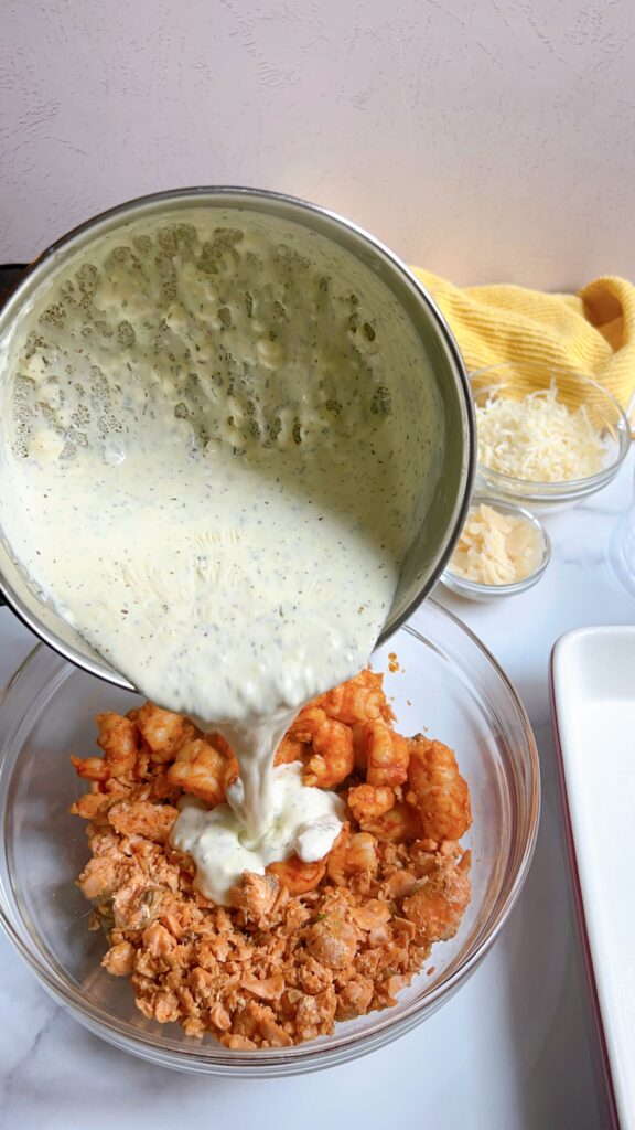 Cream sauce being poured over cooked shrimp and salmon